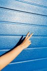 Imagem cortada de mulher mostrando símbolo de paz perto da parede azul — Fotografia de Stock