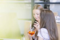 Two young female friends drinking cocktails at sidewalk cafe — Stock Photo
