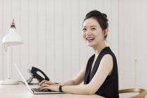 Молодая женщина работает на ноутбуке за столом — стоковое фото