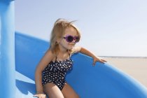 Girl on slide in swimming costume and sunglasses — Stock Photo