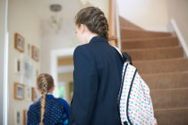 Vista posteriore di adolescente studentessa e sorella in uniforme in corridoio — Foto stock