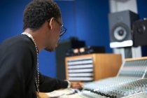 Young male college student at sound mixer in recording studio — Stock Photo