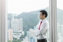 Businessman, arms folded looking out of window — Stock Photo