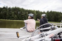 Rear view of mature couple with bicycles relaxing on pier — Stock Photo