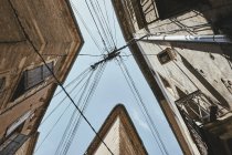 Vue en angle bas des bâtiments traditionnels et des lignes électriques contre le ciel bleu, Pezenas, région Occitanie, France — Photo de stock