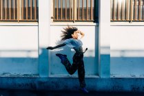 Junge Frau springt in der Nähe der Mauer, Mailand, Italien — Stockfoto