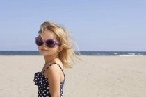 Retrato de menina na praia em traje de natação e óculos de sol — Fotografia de Stock