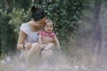 Donna accovacciata con bambina nel parco — Foto stock