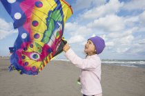 Дівчина з барвистим літаючим змієм на пляжі — стокове фото