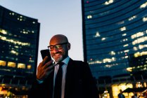Reifer Geschäftsmann nutzt nachts Smartphone — Stockfoto