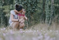 Женщина обнимает маленькую дочь в парке — стоковое фото