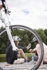 Зрелая пара в велосипедных шлемах смотрит на смартфон на пирсе — стоковое фото