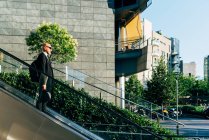 Mature businessman on moving escalator outdoors — Stock Photo