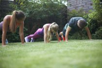 Родина робить стрибки і фізичні вправи в саду — стокове фото