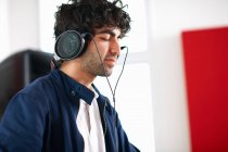 Young male college DJ student listening to music on headphones — Stock Photo