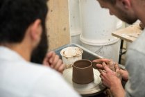 Tutor and student in art studio using pottery wheel — Stock Photo