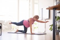 Giovane donna incinta che fa esercizio di yoga in soggiorno — Foto stock