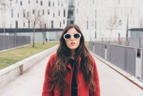 Portrait of young woman, wearing sunglasses, standing in urban environment — Stock Photo
