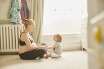 Side view of pregnant woman and daughter in bedroom — Stock Photo
