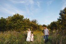Famiglia che cammina insieme nell'erba alta — Foto stock