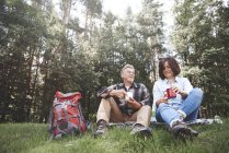 Reifes Paar entspannt sich mit Blechbechern im Gras — Stockfoto