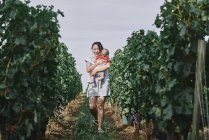 Woman carrying baby girl in vineyard — Stock Photo