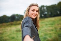 Личная перспектива молодой женщины, ведущей рукой в поле — стоковое фото
