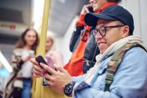 Young man looking at smartphone on city tram — Stock Photo