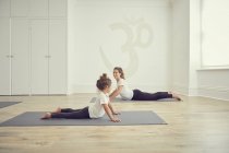 Madre e hija en estudio de yoga, en posiciones de yoga - foto de stock