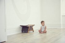 Тоддлер, сидящий на полу в голой комнате — стоковое фото