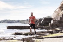 Giovane uomo che corre lungo il bordo del mare — Foto stock