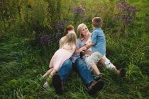 Parents and children lying in tall grass together — Stock Photo