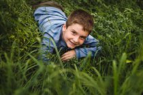 Rapaz a olhar para a câmara no campo verde gramado — Fotografia de Stock