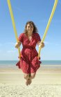 Frau in rotem Kleid schwingt am Strand, zoutelande, zeeland, niederland, europa — Stockfoto