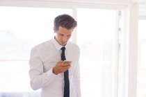 Бизнесмен смотрит на смартфон в гостиной — стоковое фото