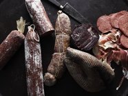 Top view of selection of cured meats on black background — Stock Photo