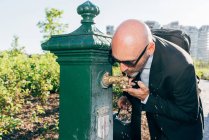 Зрелый бизнесмен, использующий фонтан воды — стоковое фото