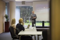 Colleagues in conference room watching presentation on projection screen — Stock Photo