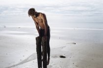 Junger Mann trainiert auf hölzernen Strandpfosten — Stockfoto