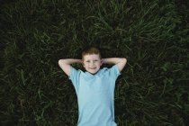 Overhead portrait of red haired boy lying on grass — Stock Photo