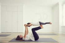 Madre e figlia in studio di yoga, figlia in equilibrio sulle gambe madri — Foto stock