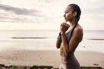 Молода жінка біжить, готуючись бігати на пляжі — стокове фото
