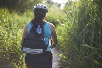 Ciclista equitazione attraverso il campo con erba alta — Foto stock