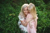 Мати і дочка у високій траві дивиться на камеру посміхаючись — стокове фото