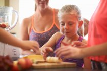 Девочка и семья готовят фрукты для смузи на кухне — стоковое фото