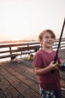 Niño en muelle con caña de pescar sonriendo, Goleta, California, Estados Unidos, América del Norte - foto de stock