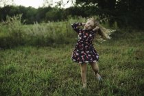Loira de cabelos menina correndo e puxando um rosto no campo — Fotografia de Stock