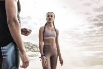Young female runner looking at young man on beach — Stock Photo