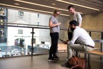 Uomo con colleghi sul mezzanino in edificio per uffici con tablet digitale — Foto stock