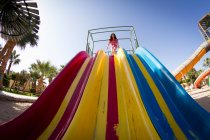 Visão de ângulo baixo da menina se preparando para deslizar no slide do parque de jogos — Fotografia de Stock